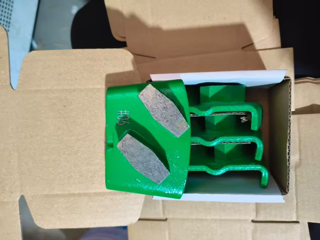 A green cast hexagonal-segment grinding block with two diamond pads, in an opened carton