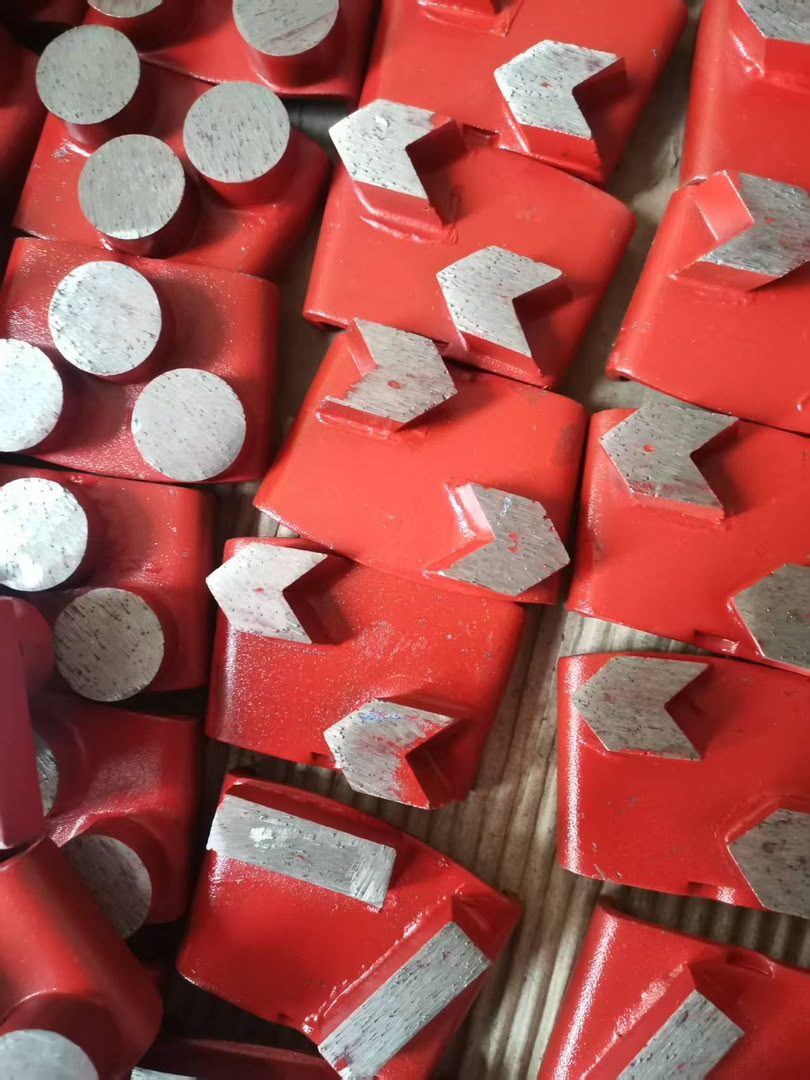 A tray of red diamond grinding bits, round and chevron segments, packed face up