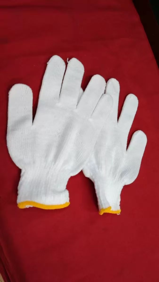 A pair of white knitted cotton gloves with yellow cuffs