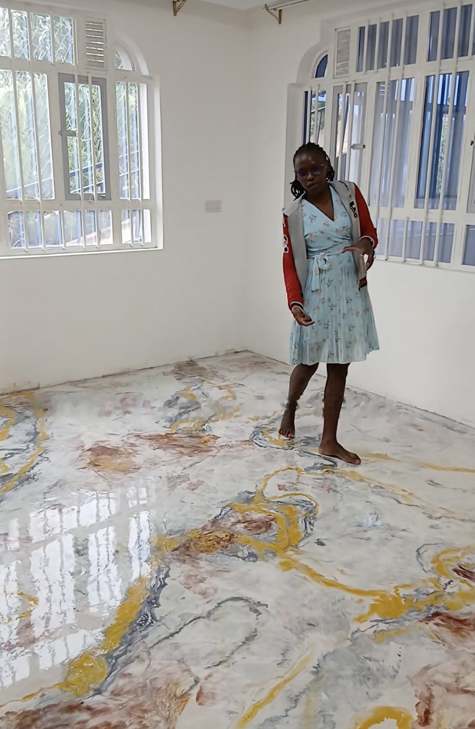 Finished marble-effect epoxy floor in white, gold and rust in a bright room, a client standing on it barefoot